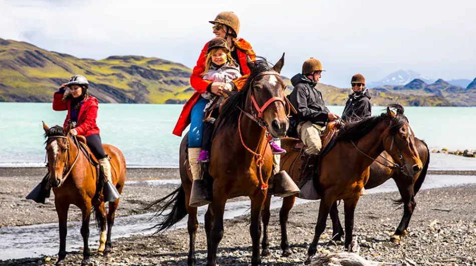 Family horseback riding in front of a lagoon