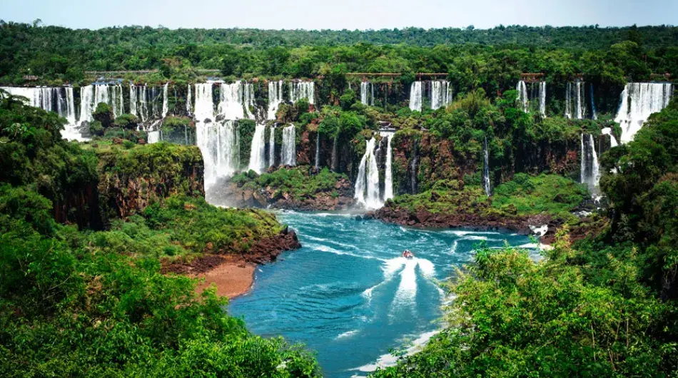 Iguazu falls with turquoise water surrounded by lush green forest