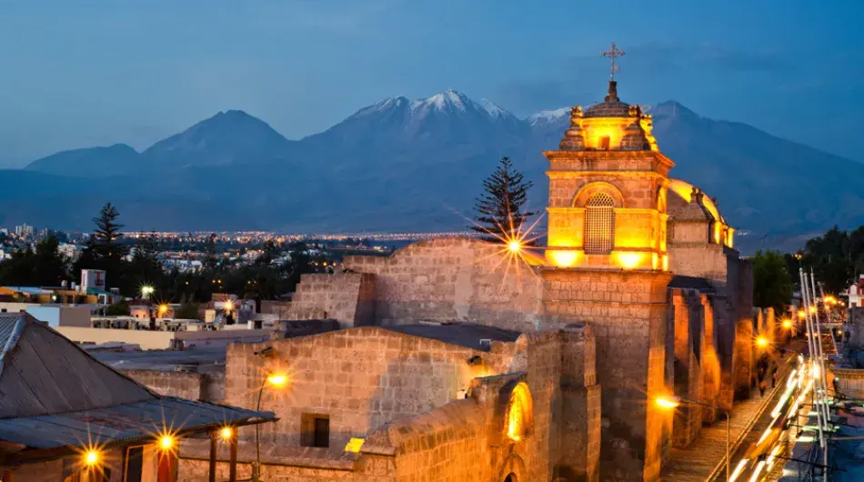 Arequipa santa catalina convent at dusk with yellow lights and mountain in background