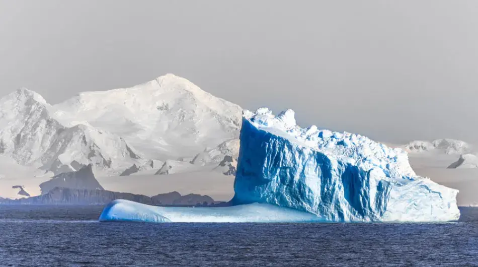 Blue iceberg floating in icy Antarctic waters