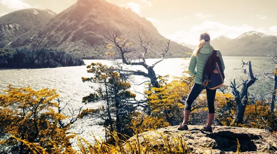 Female hiker standing near lake during sunset