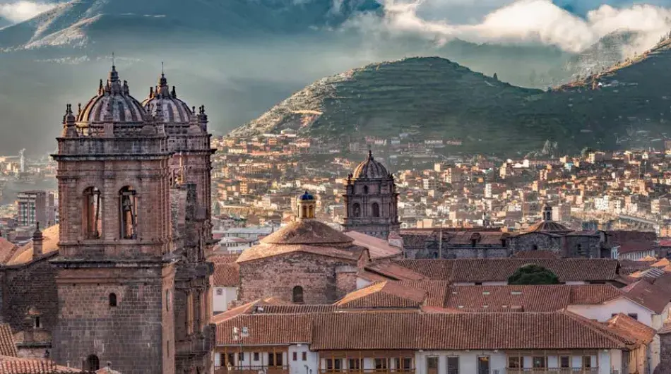 Cusco historic centre main cathedral bell tower with foggy mountains landscape