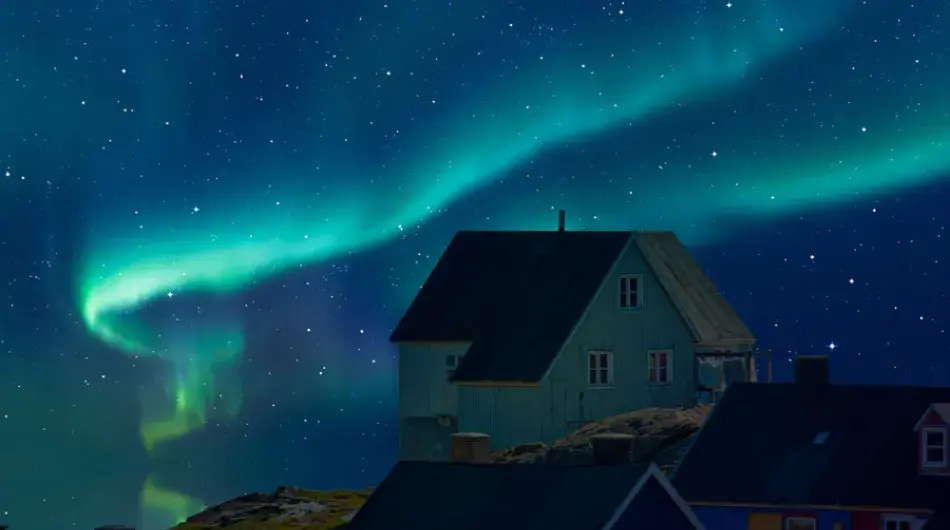 Aurora Borealis (Northern Lights) overhead of homes of east Greenland in Arctic night