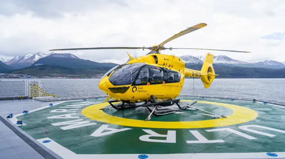 Quark yellow Flightseeing helicopter on Ultramarine's helipad in Ushuaia with photo by Michelle Sole