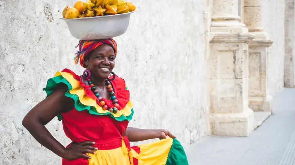 Colombian lady in a colourful dress with a fruit baskets on her head
