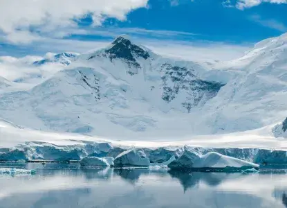 calm reflection in bay in Antarctica with snowy mountains down to waters edge) 