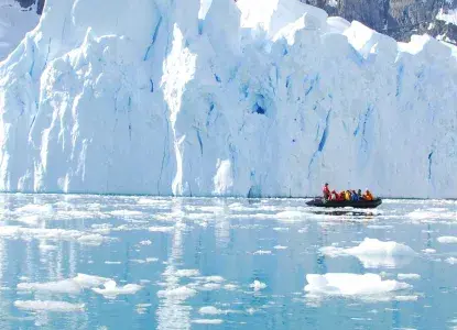 zodiac with tourists in front of a glacier in Antarctica) 