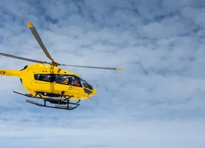 Quark yellow Flightseeing helicopter in the clear blue sky with few clouds in Antarctica with photo by Michelle Sole) 