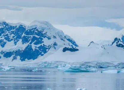 antarctica-hero-new-size-3.jpg Panoramic Antarctica landscape with snowy mountains in the background and small icebergs in the water in front of them)